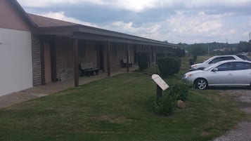 A motel with a covered parking area, a grassy lawn, and a signboard.