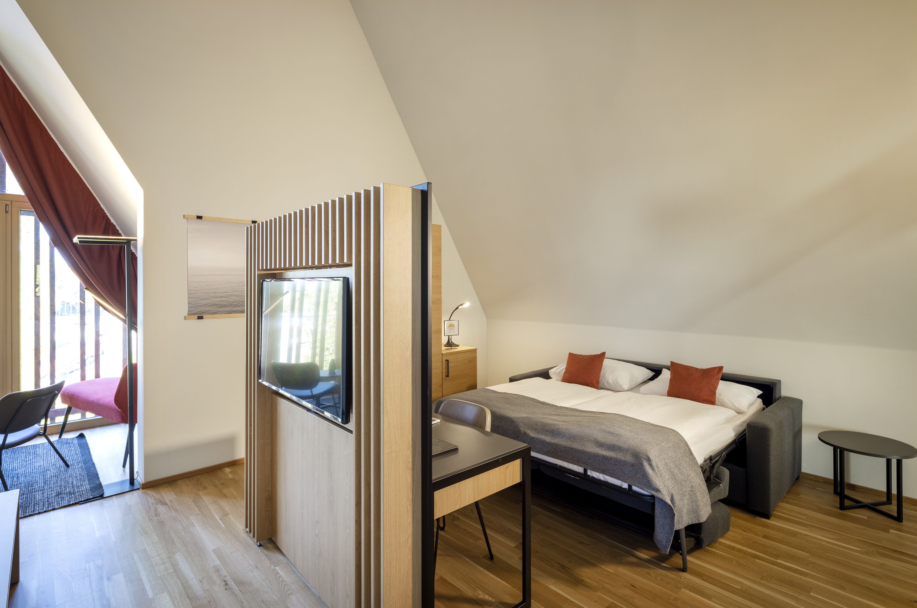 Ein modernes Schlafzimmer mit Bett, Schreibtisch und Fernseher.