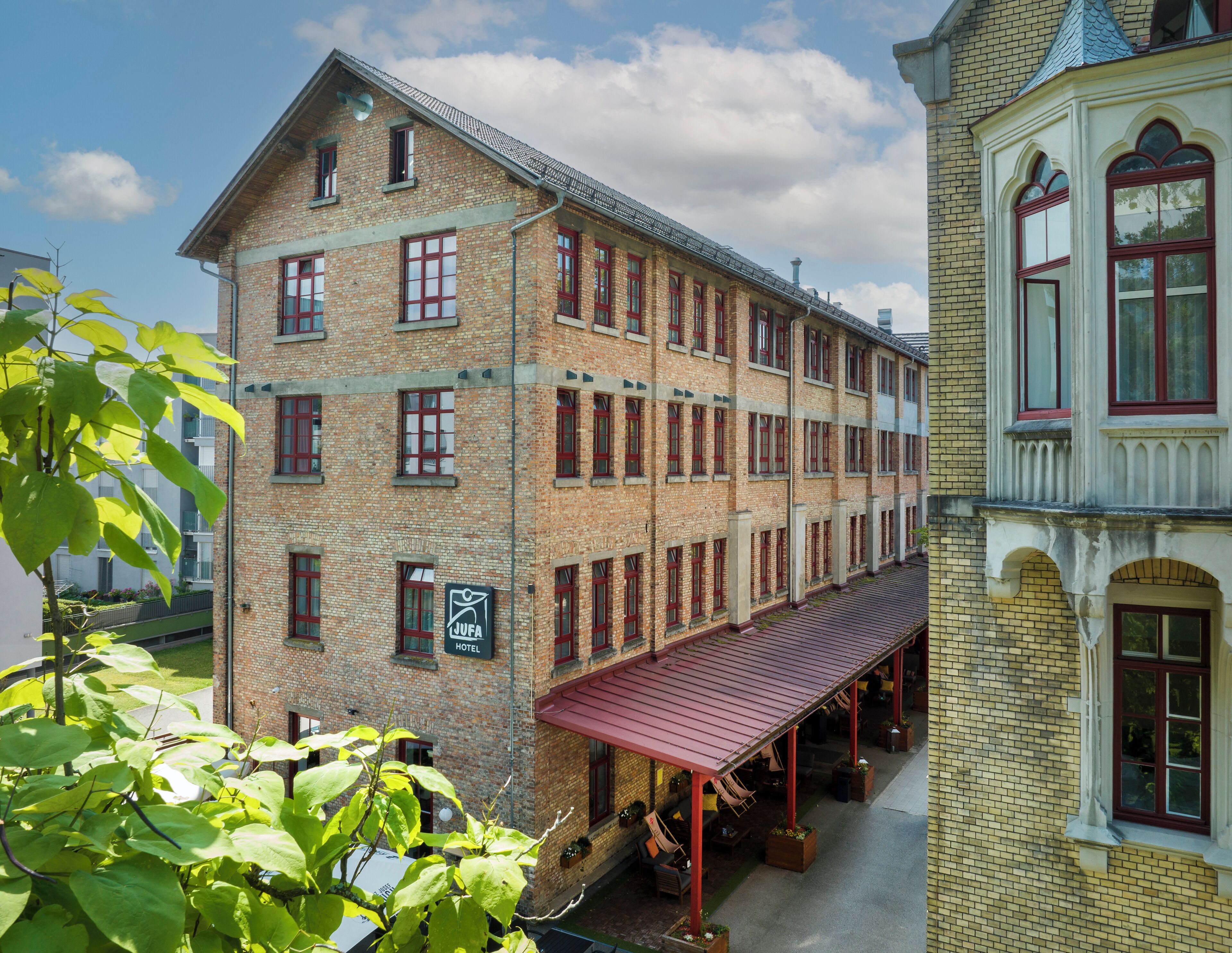 A historic building with a red-brick facade, multiple windows, and a covered outdoor seating area.