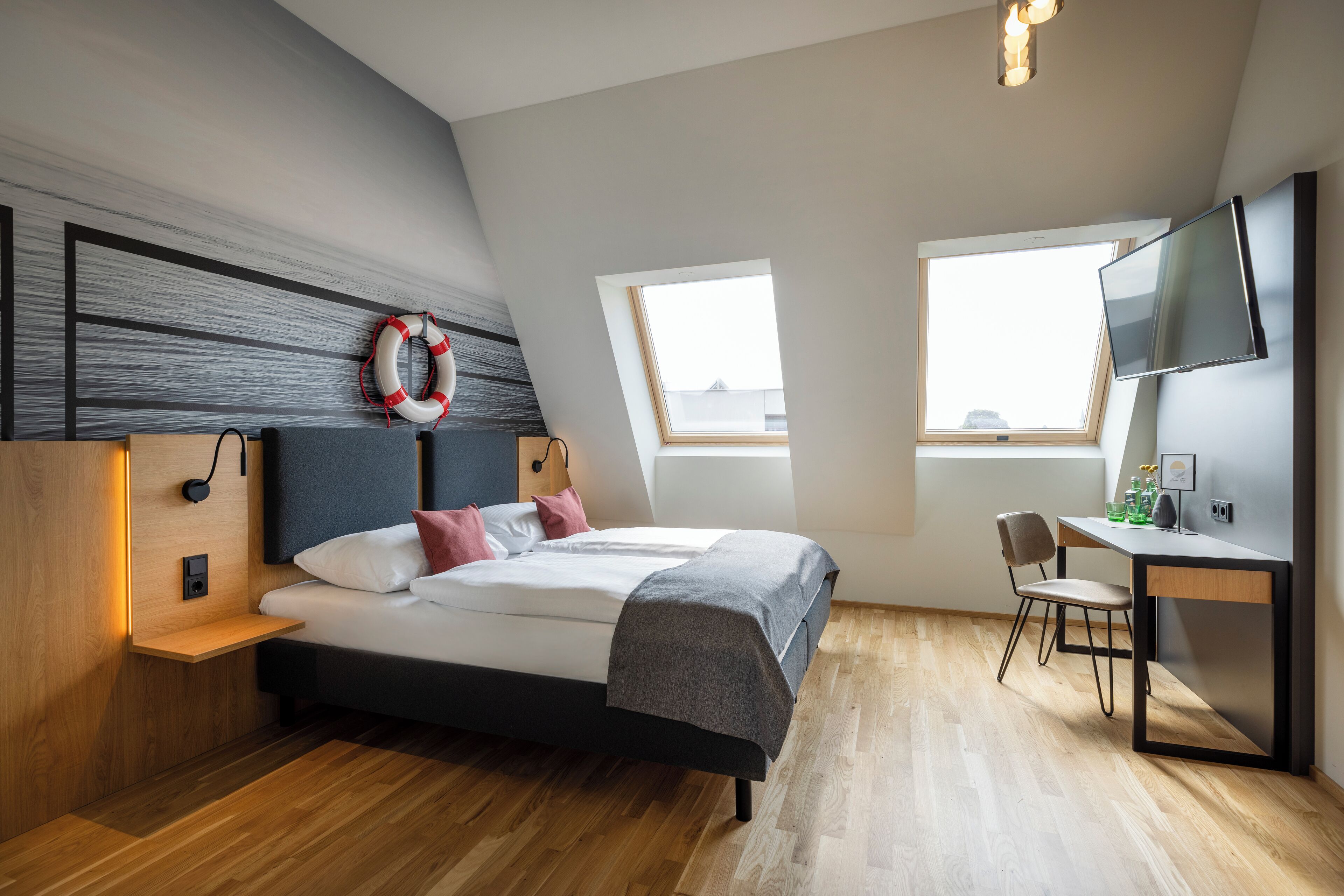A modern bedroom with a bed, bedside tables, a desk, and a TV.