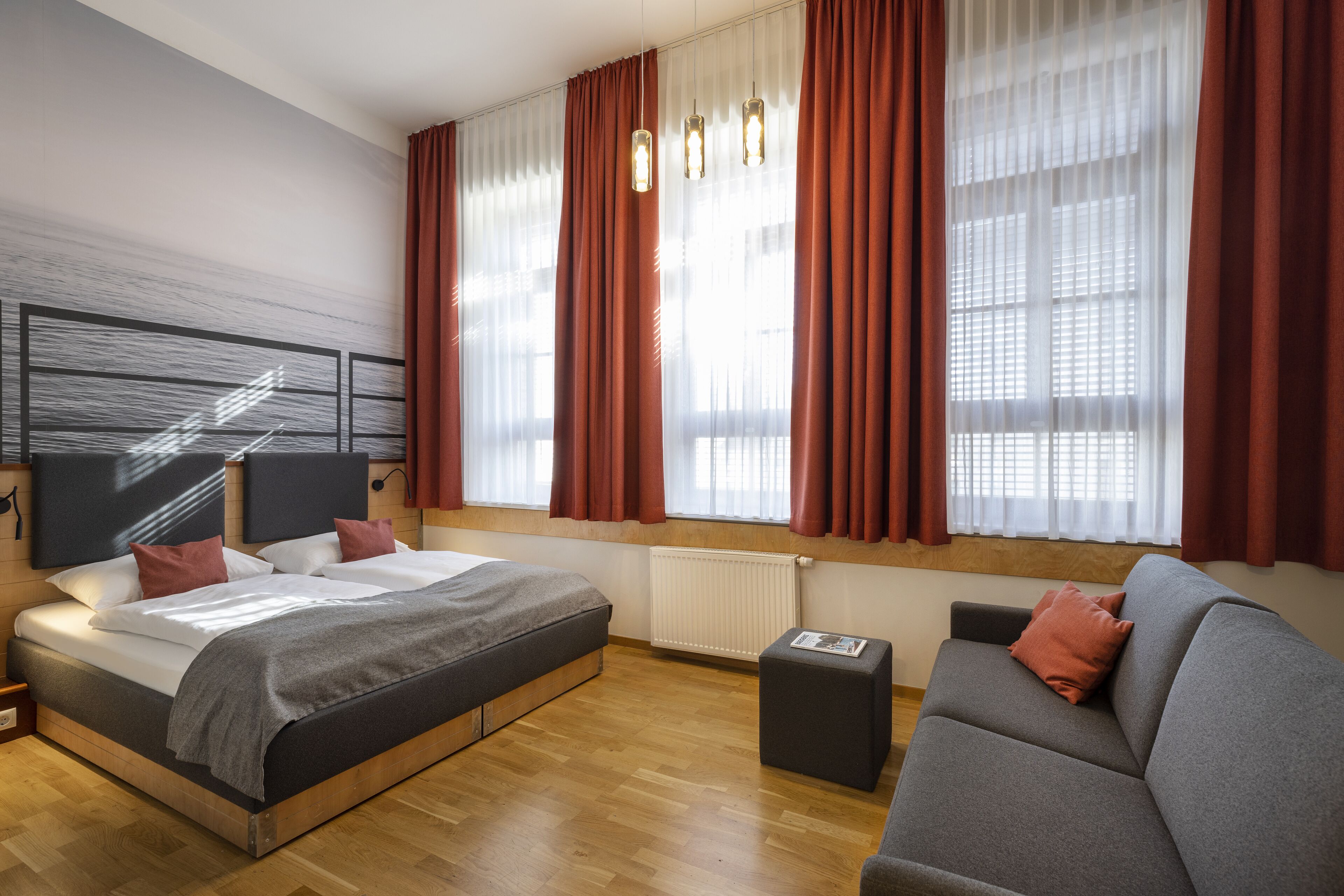 Une chambre moderne avec un grand lit, un canapé et une fenêtre avec des rideaux.