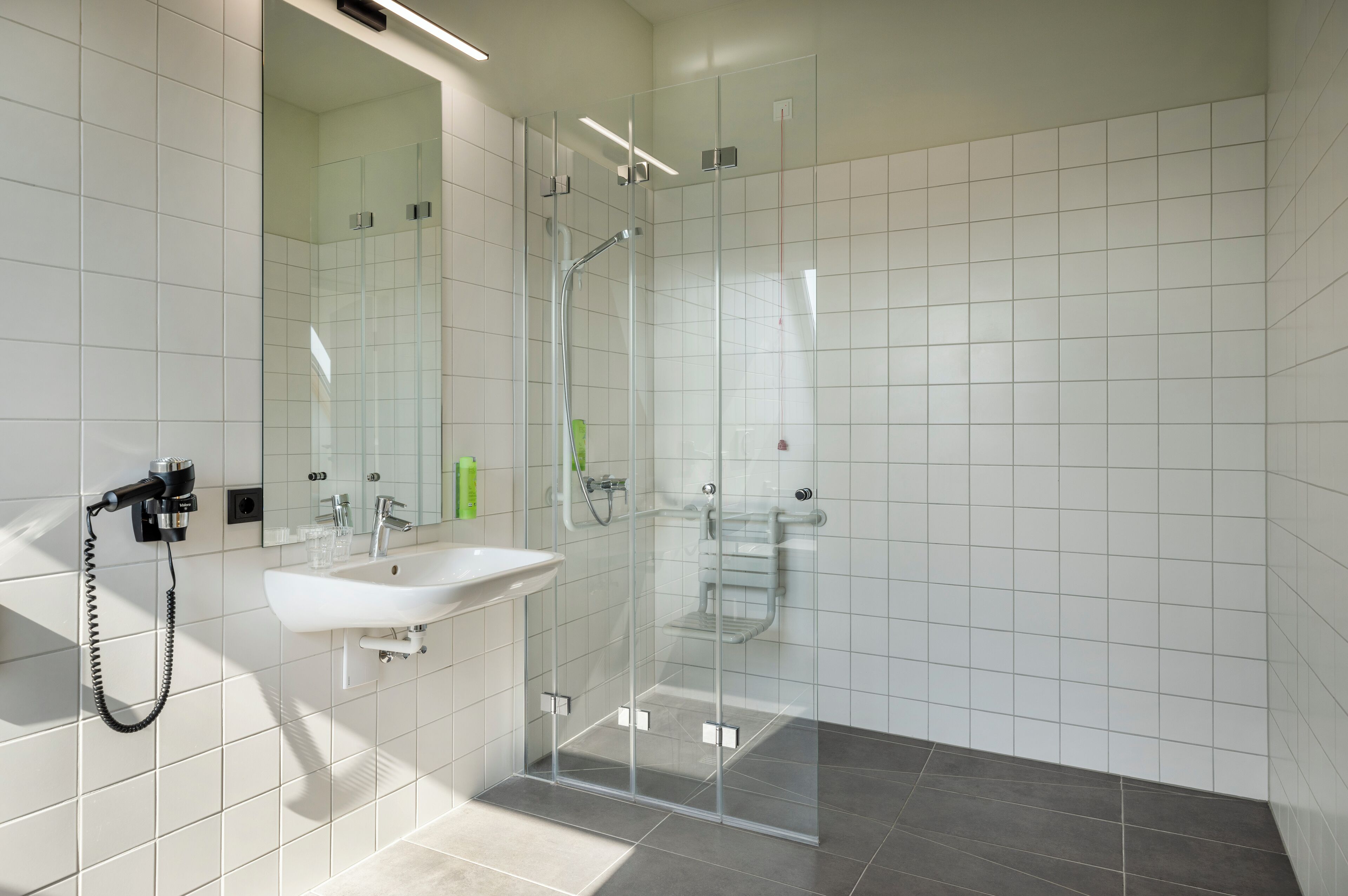 Un bagno moderno con doccia vetrata, lavandino bianco e specchio.