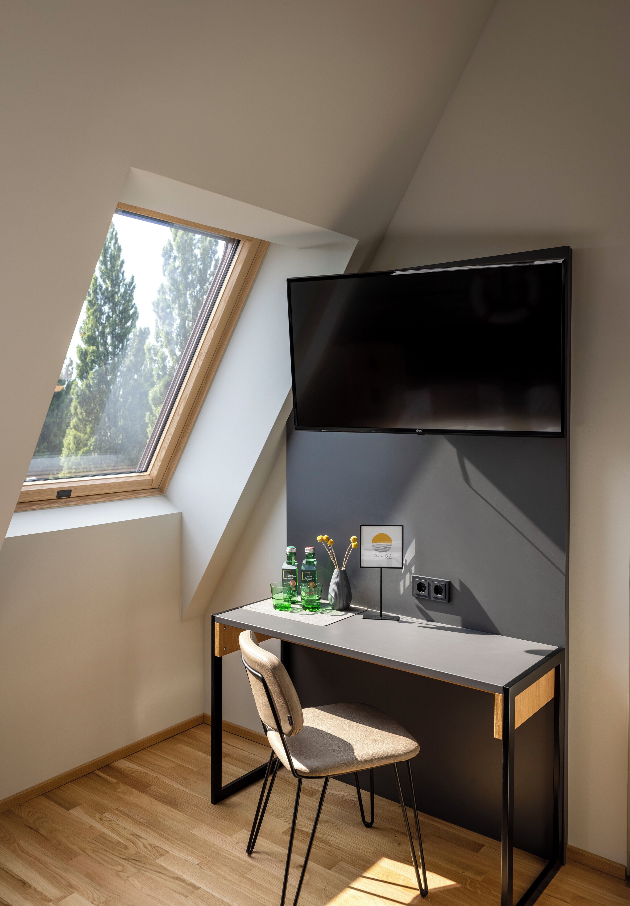 Ein moderner, kompakter Arbeitsbereich mit Schreibtisch, Stuhl und einem großen Flachbildfernseher an der Wand.