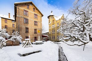 A snow-covered courtyard with a brick building, a statue, and a wooden fence. - JUFA Hotel Bregenz (Bregenz)