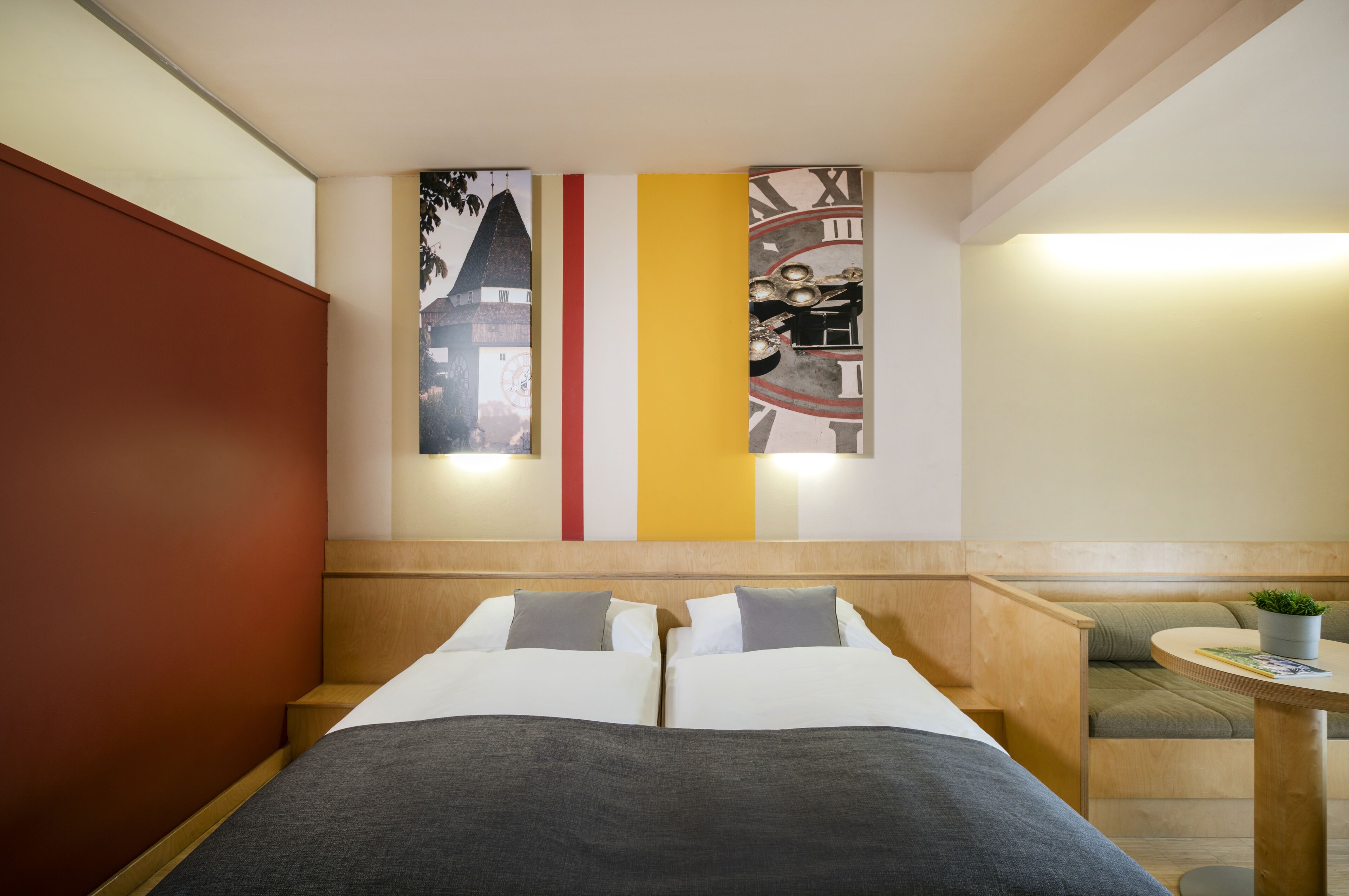 Una habitación de hotel con una cama, una mesita con una planta y una pared con tres paneles verticales.