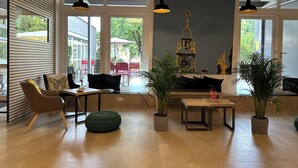 A modern interior with a seating area, large windows, and potted plants.