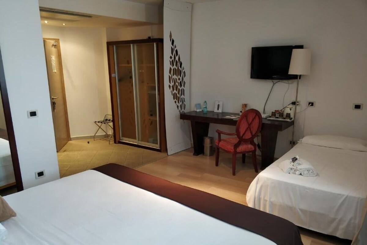 Une chambre d’hôtel comprenant un lit, un bureau avec une chaise, une télévision et une porte coulissante.