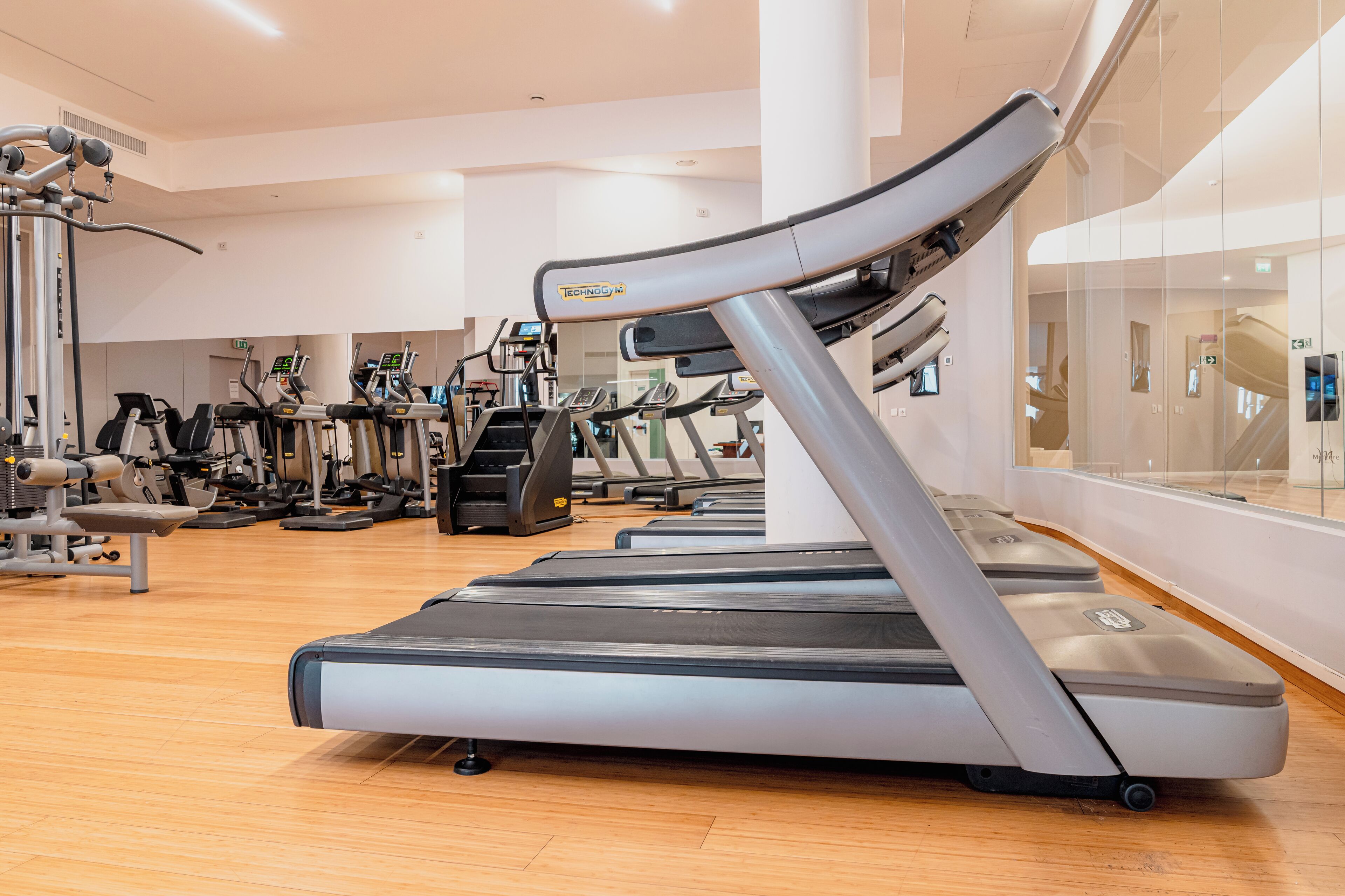 A gym with multiple treadmills, ellipticals, and weight machines.