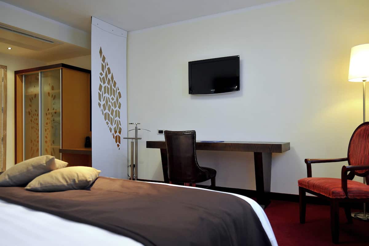 Une chambre d’hôtel avec un lit, un bureau, une chaise, une télévision et une lampe.