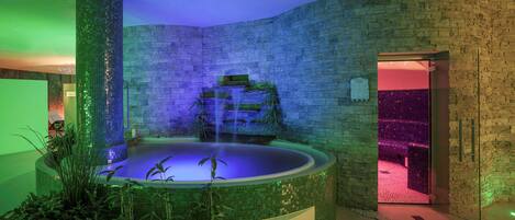 A spa area with a circular hot tub, a waterfall feature, and a stone wall.