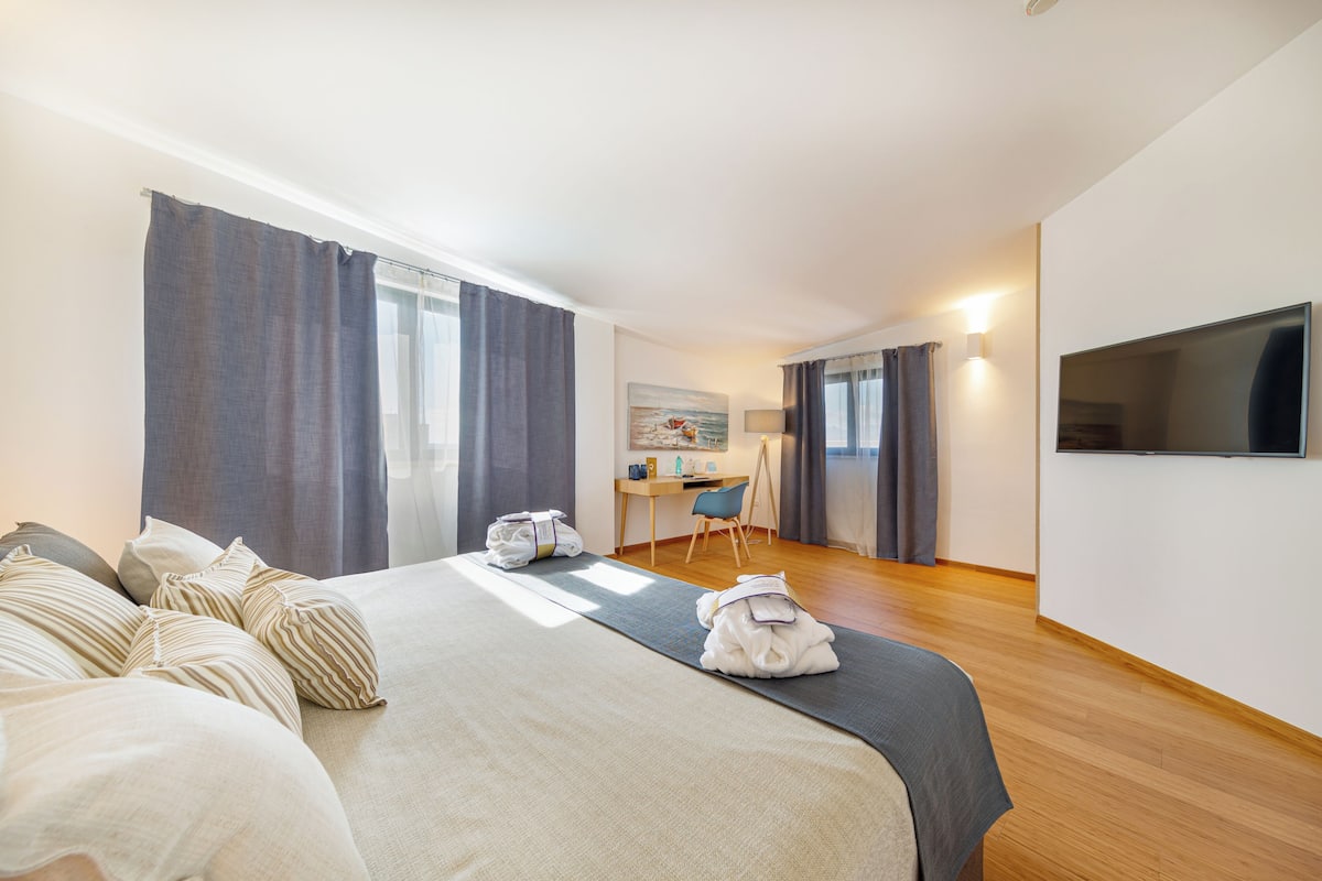 Une chambre d’hôtel avec un lit, un bureau, une chaise et un téléviseur.