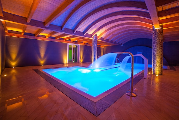 Ein beheiztes Hallenbad mit Holzboden und hoher, gewölbter Decke.