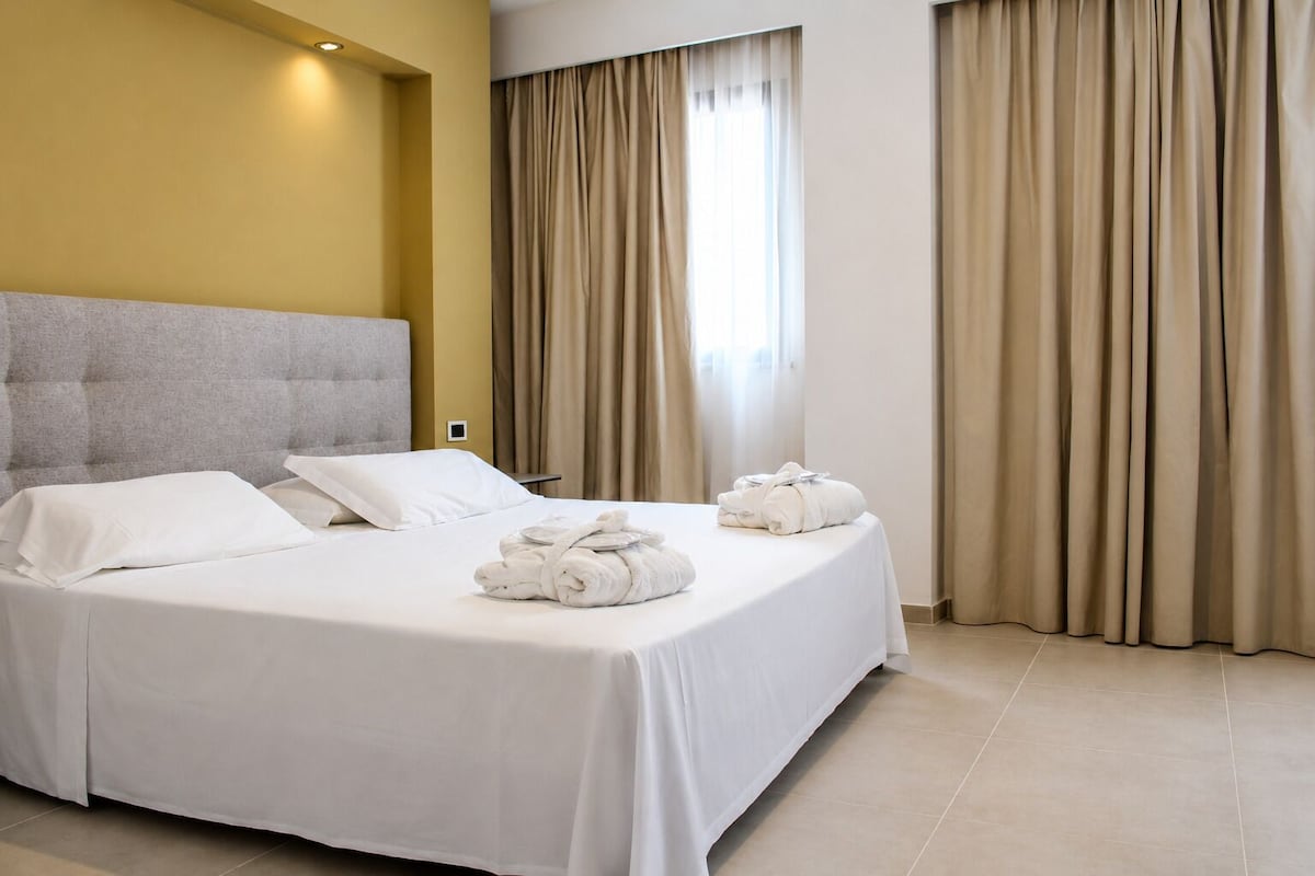 Une chambre d’hôtel avec un grand lit, une tête de lit et un ensemble de serviettes posées sur le lit.