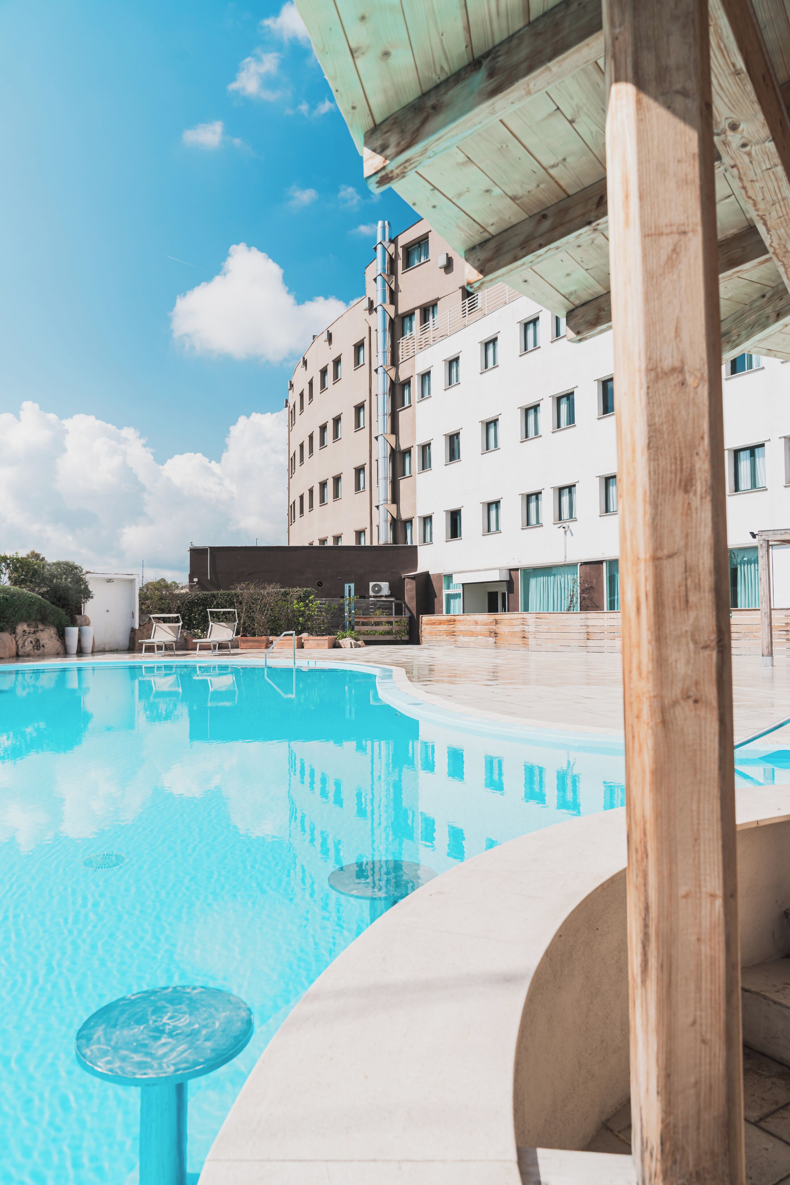 Una piscina con sillas de descanso y un edificio al fondo.