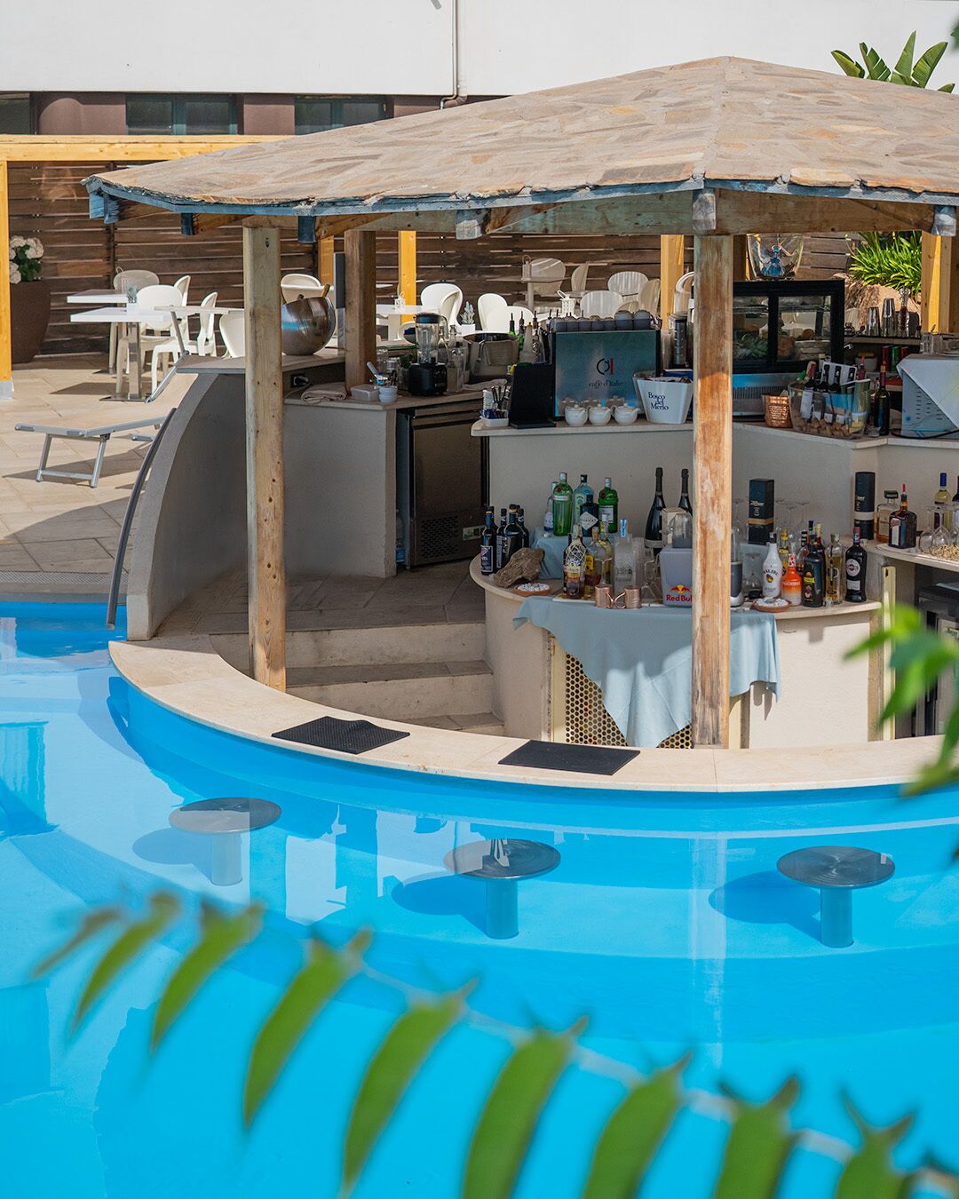 A poolside bar area with a wooden pergola, bar counter, and seating.
