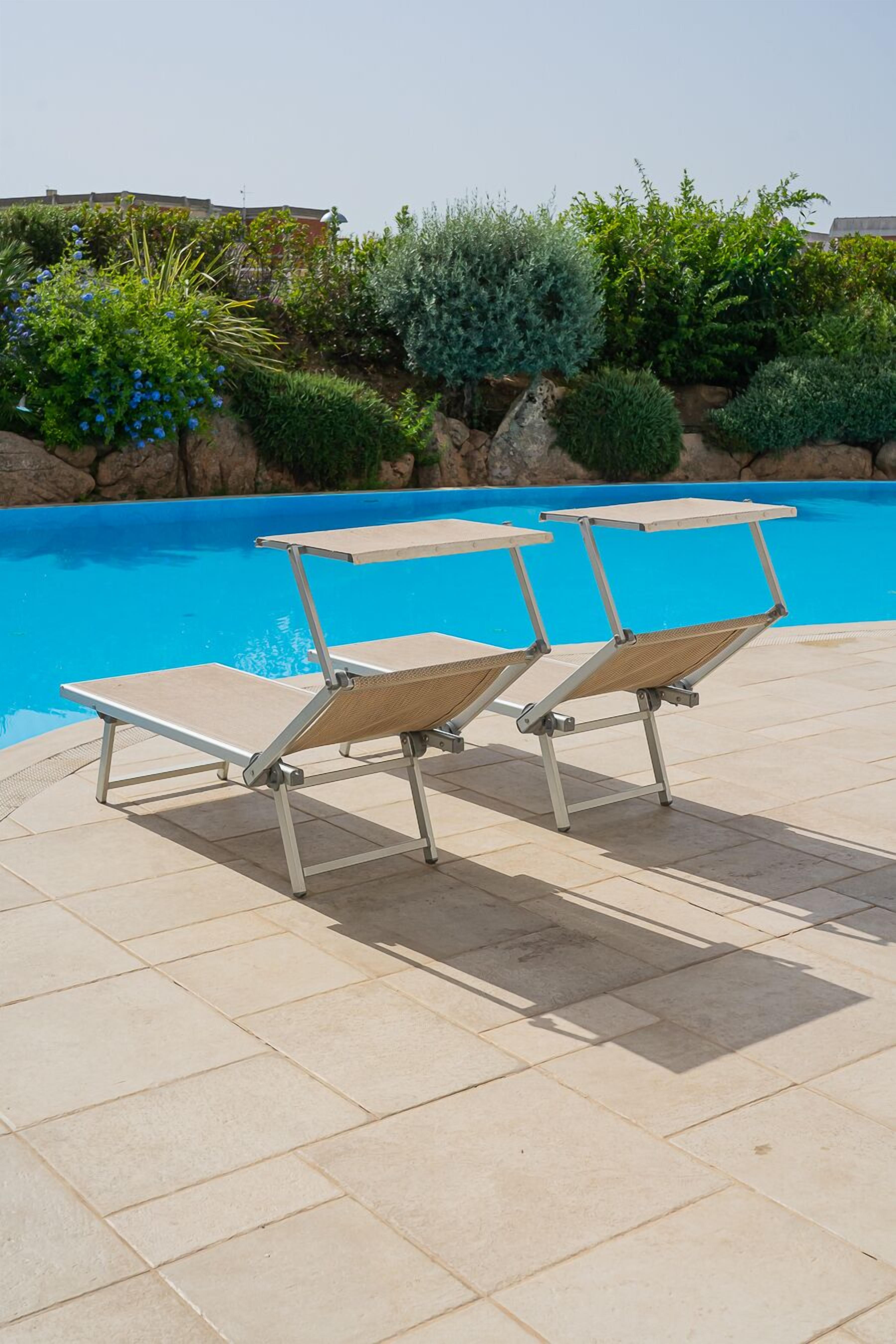 A poolside area with two sun loungers and a clear blue pool.