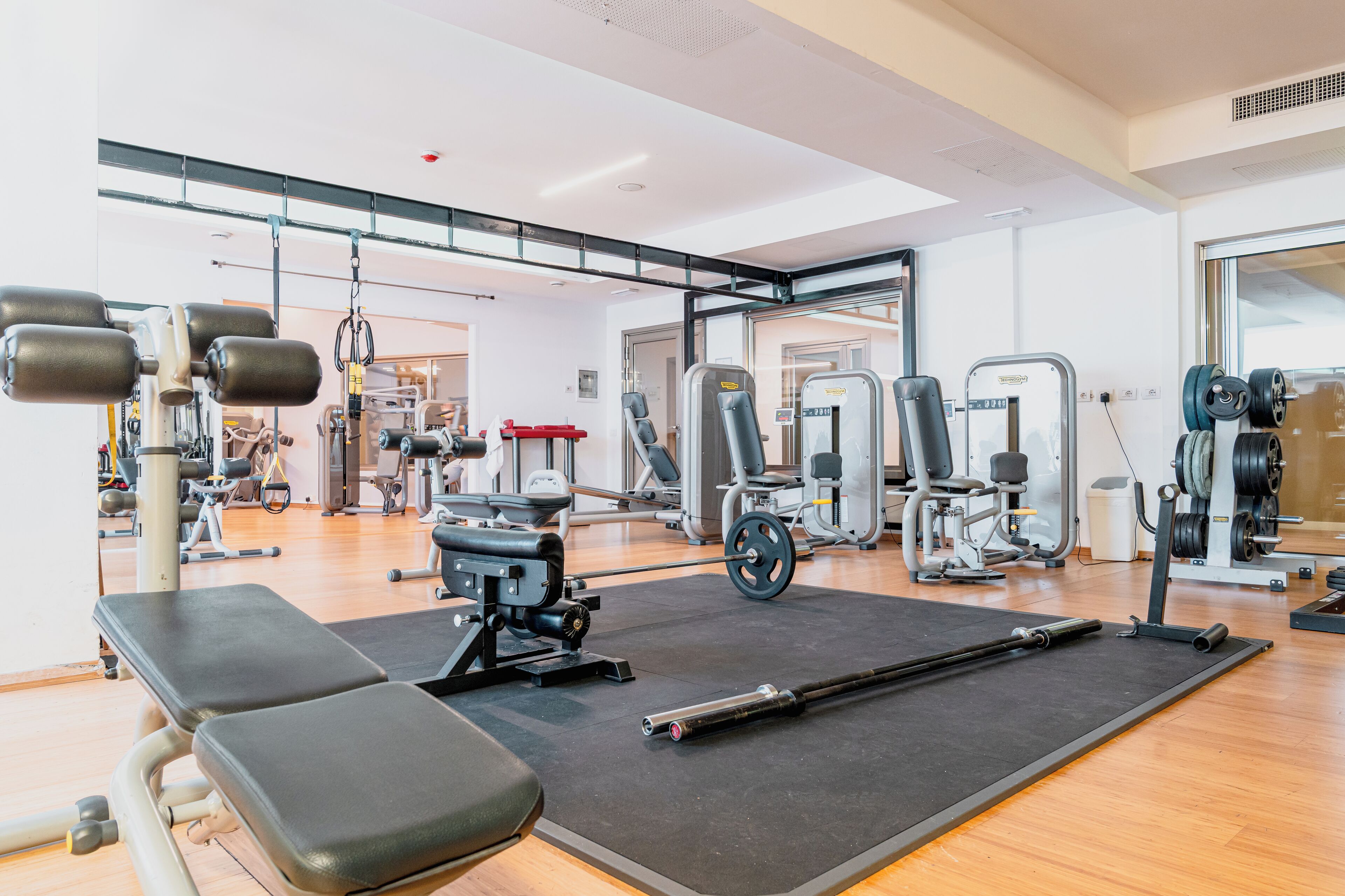 A gym with exercise equipment, benches, and a mirrored wall.