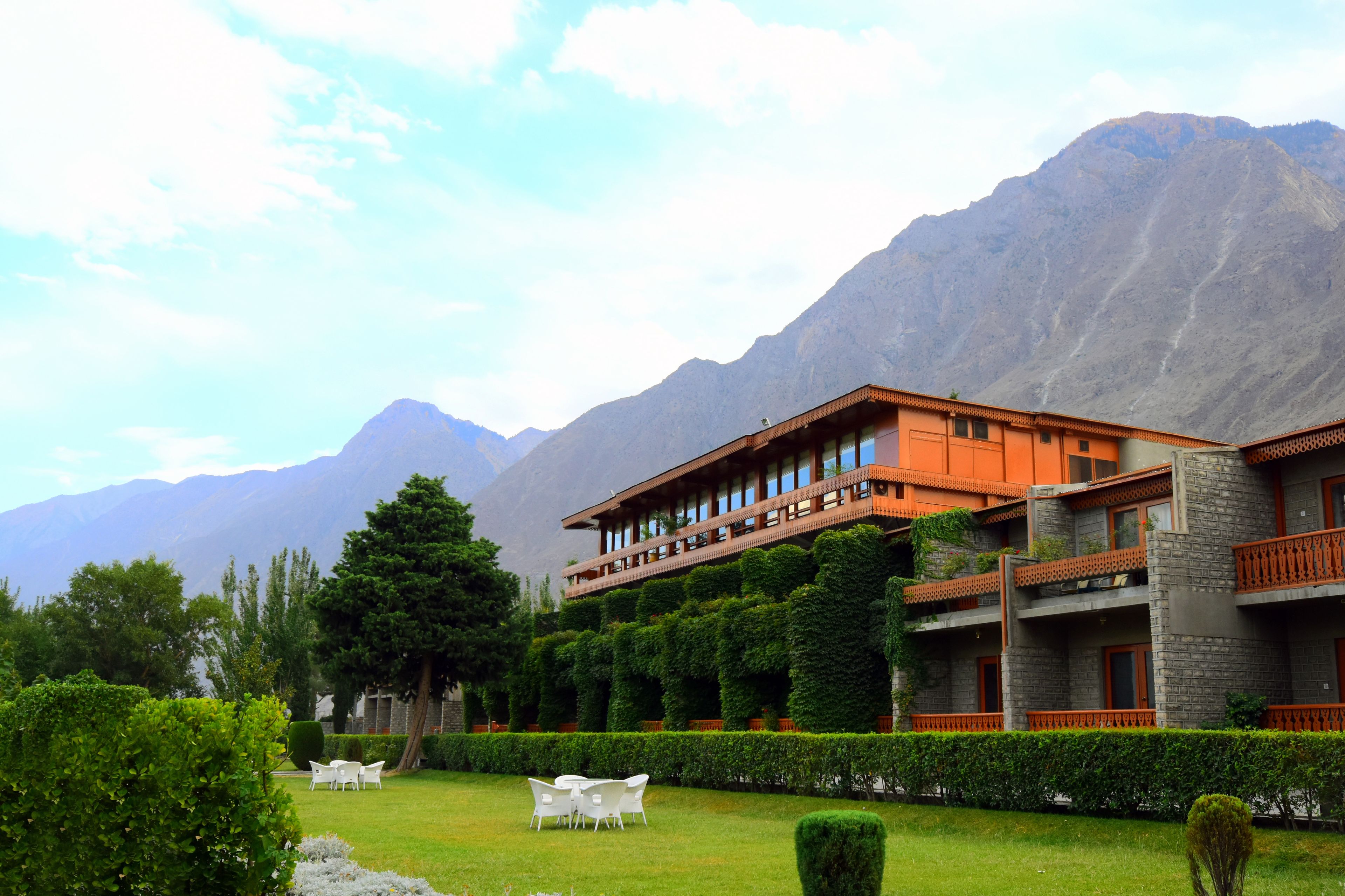 A hotel with a garden, outdoor seating, and mountain views.