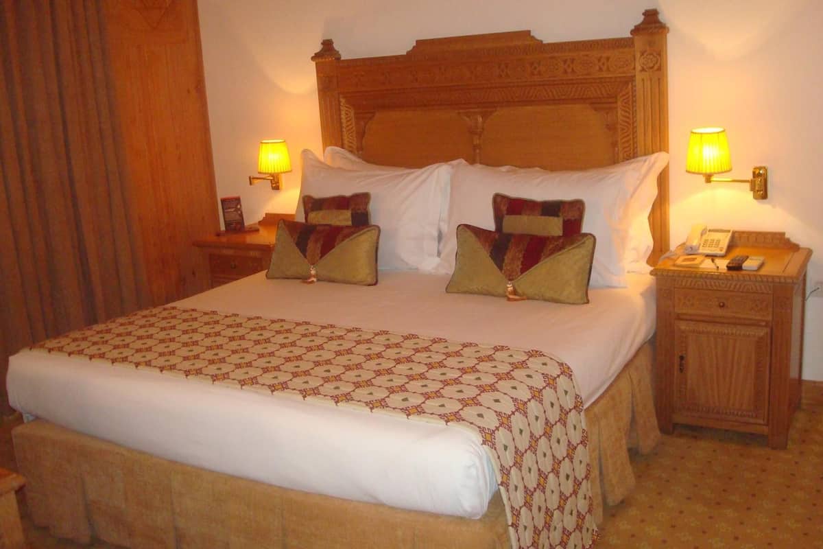 Ein Hotelzimmer mit einem großen Bett, zwei Nachttischen und einem Beistelltisch.