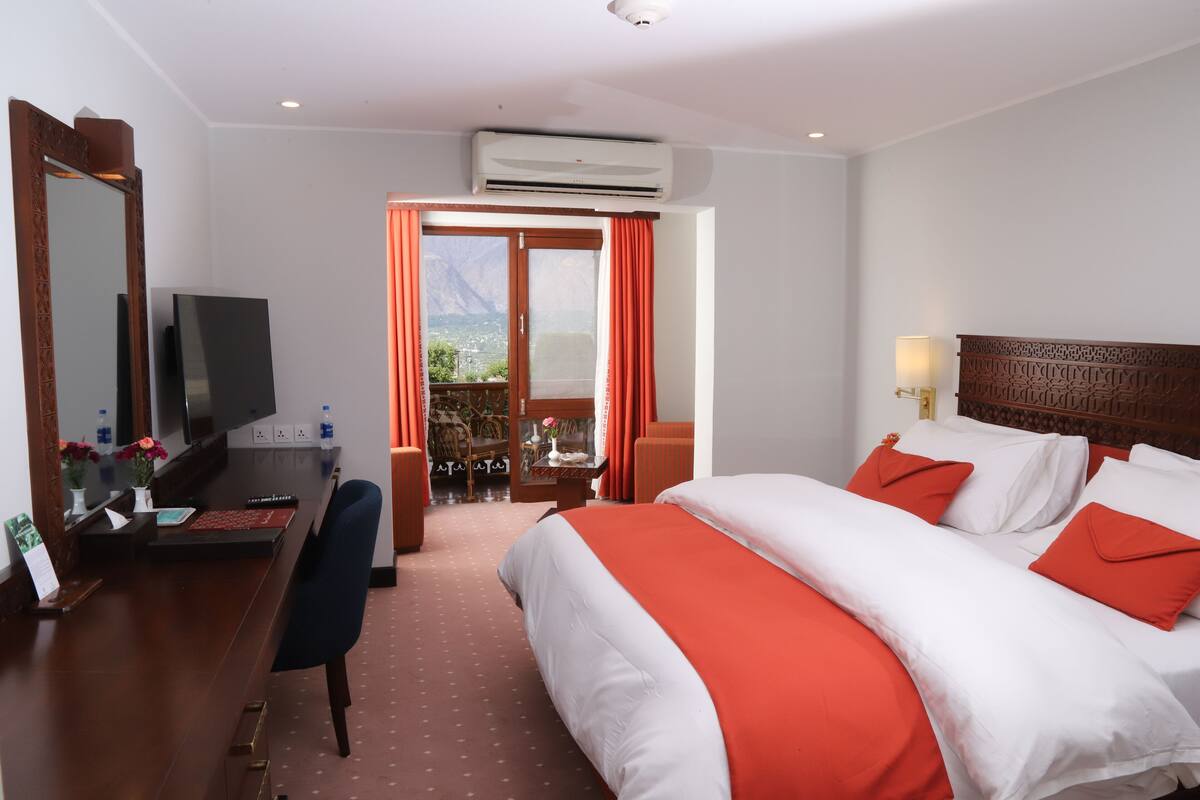 Ein Hotelzimmer mit Bett, Schreibtisch und Fernseher.