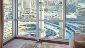 Una habitación con amplios ventanales que ofrecen vistas a un paisaje urbano, una alfombra y una pequeña mesa.
