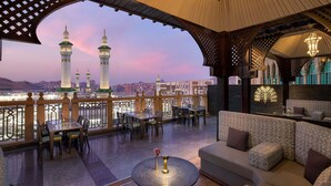 Un salón en la azotea con vistas a un paisaje urbano y los minaretes de una mezquita.
