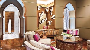 Un vestíbulo moderno con piso de madera, un área de estar con sillones acolchados, un espejo decorativo y una lámpara de diseño único.