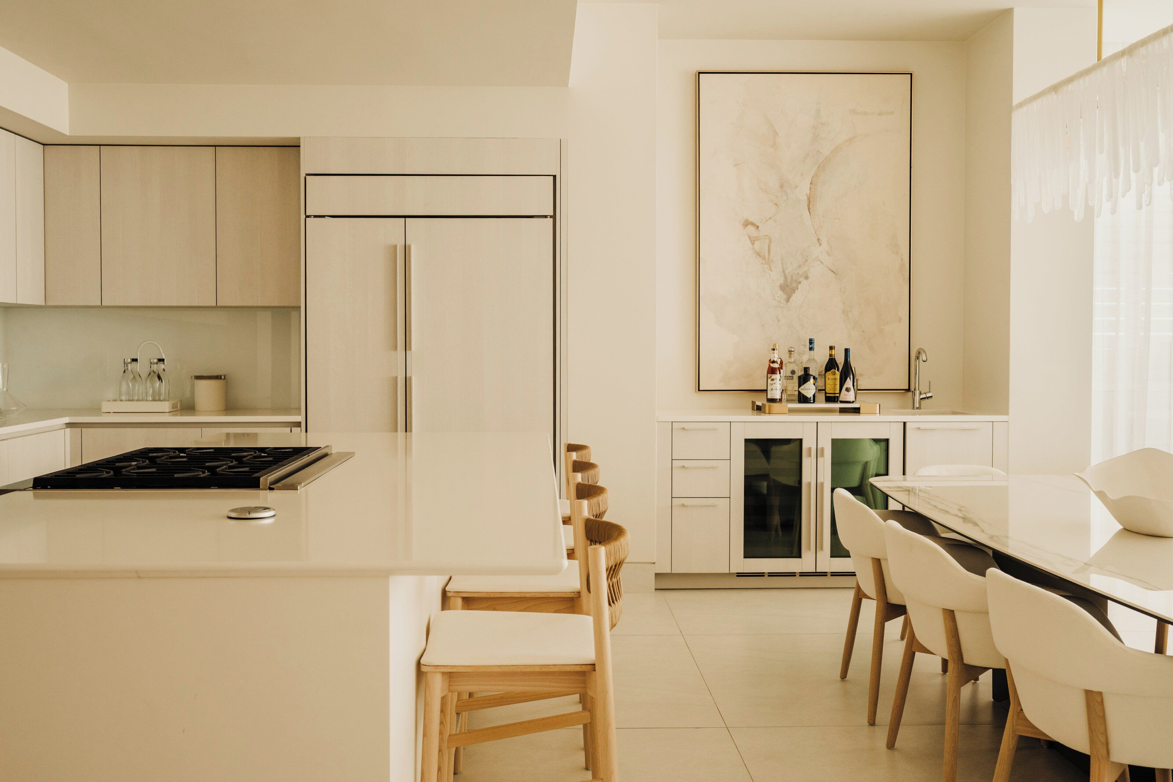 Une cuisine moderne avec un îlot central, des chaises en bois, une table à manger et un grand tableau abstrait accroché au mur.