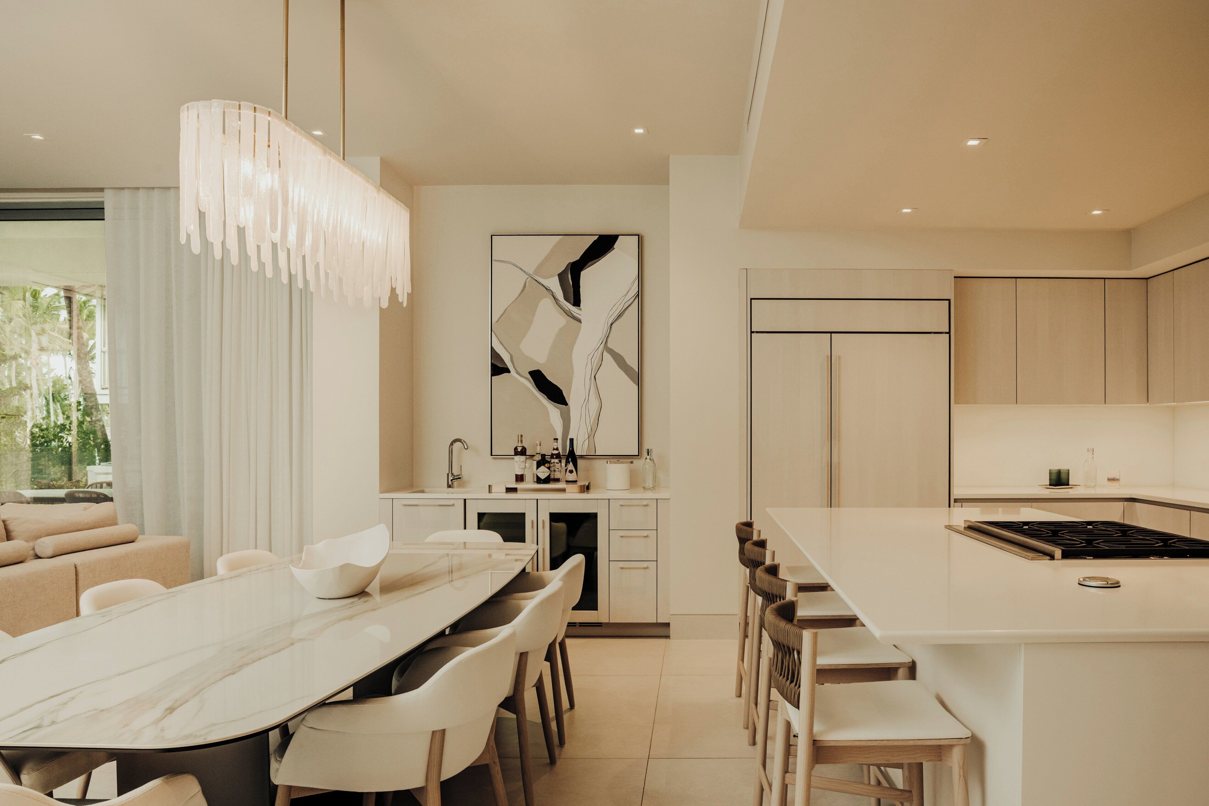 Una cocina moderna con una isla central, un comedor con mesa de mármol y una sala de estar con sofá.