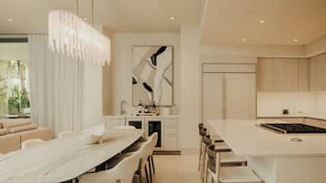 Una cocina moderna con una isla central, un comedor con mesa de mármol y una sala de estar con sofá.