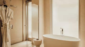 A modern bathroom with a freestanding bathtub, a glass shower enclosure, and a toilet.