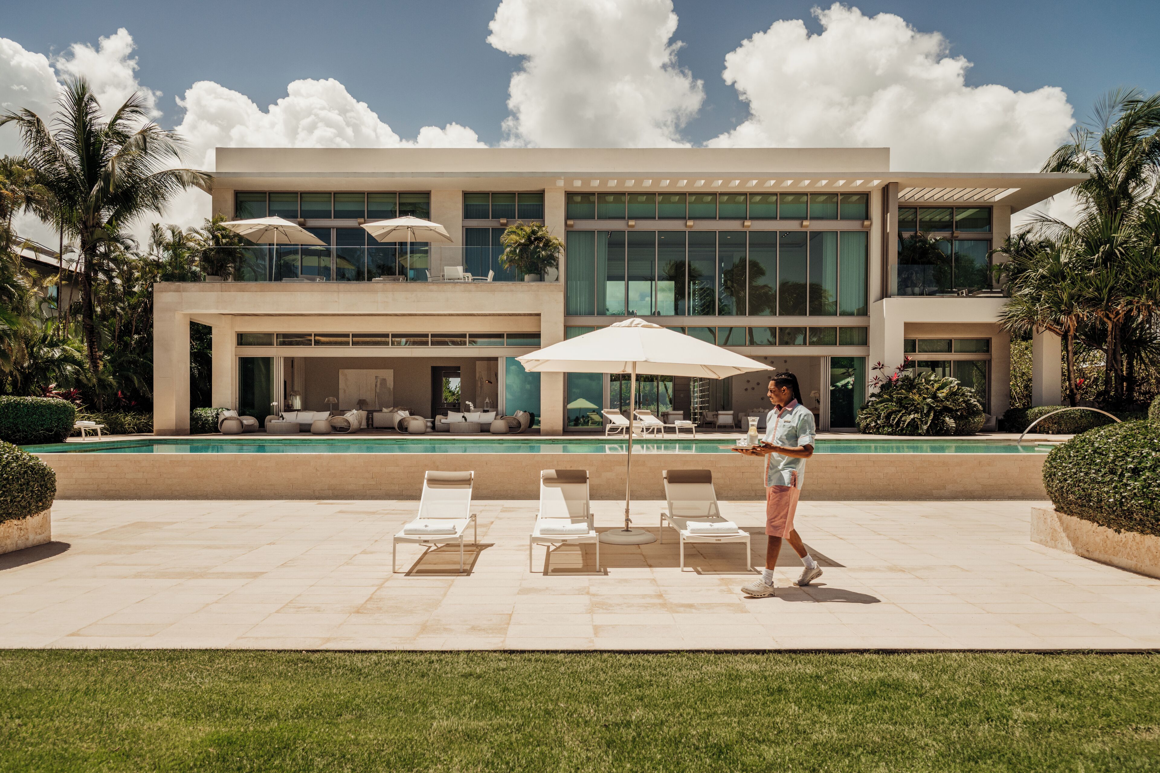 Un bâtiment moderne doté d’une piscine, de chaises longues et de parasols.