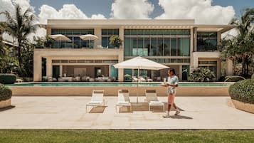 Un bâtiment moderne doté d’une piscine, de chaises longues et de parasols.