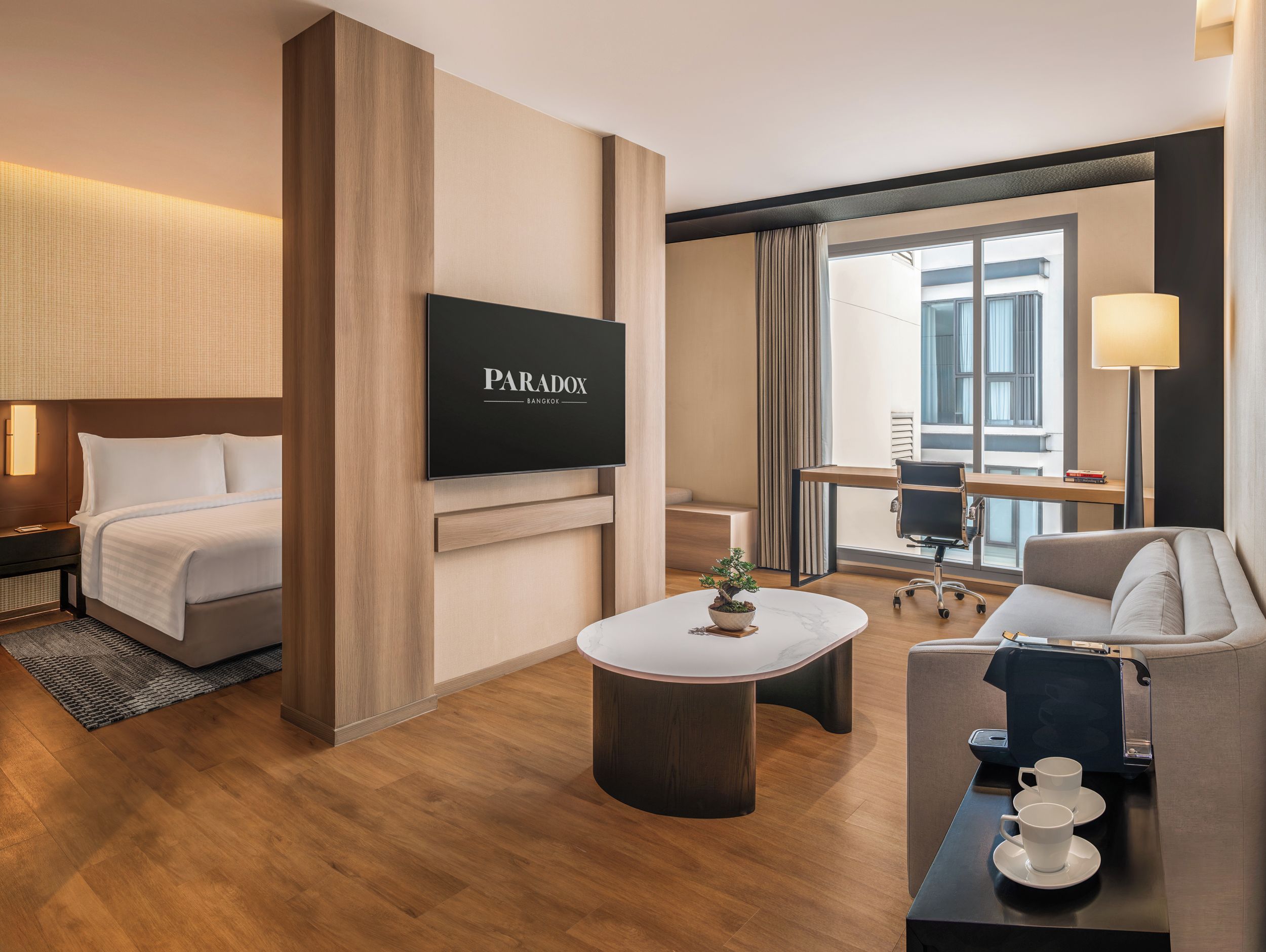 A hotel room with a bed, a TV, a desk, a coffee table, and a sofa.