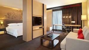 A hotel room with a bed, a TV, a desk with a laptop, a sofa, and a lamp. - Paradox Bangkok Sukhumvit (Bangkok)