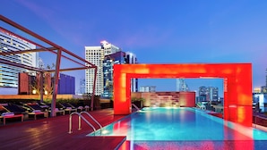 A rooftop pool with a red arch structure, lounge chairs, and a city skyline in the background. - Paradox Bangkok Sukhumvit (Bangkok)