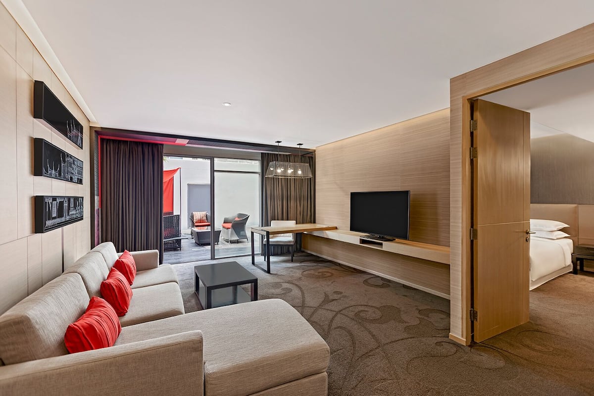 A modern hotel room with a sofa, a TV, a desk, and a bed.
