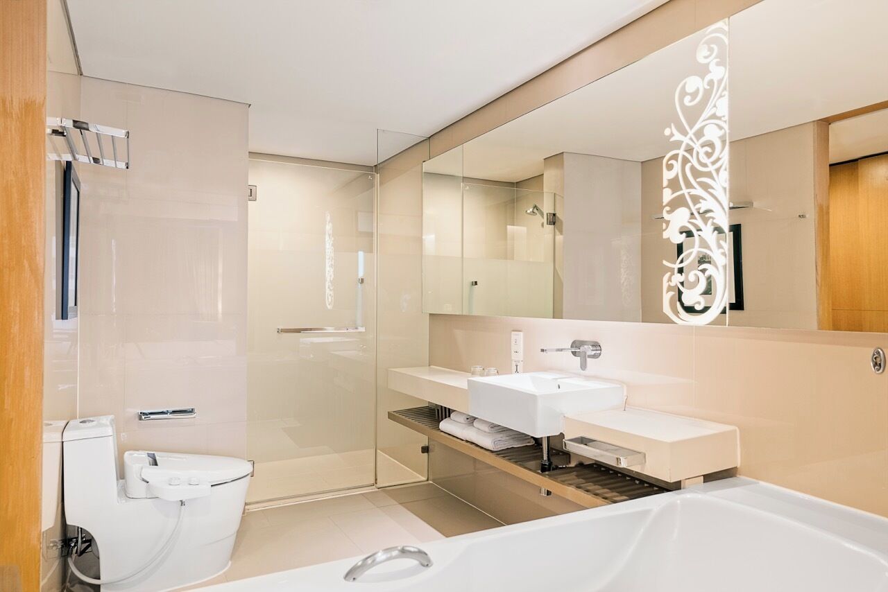 A modern bathroom with a glass shower enclosure, a white toilet, and a large mirror with decorative elements.