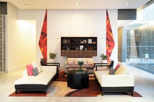 Un vestíbulo moderno con dos sofás blancos, una mesa de centro y un mueble decorativo en la pared.