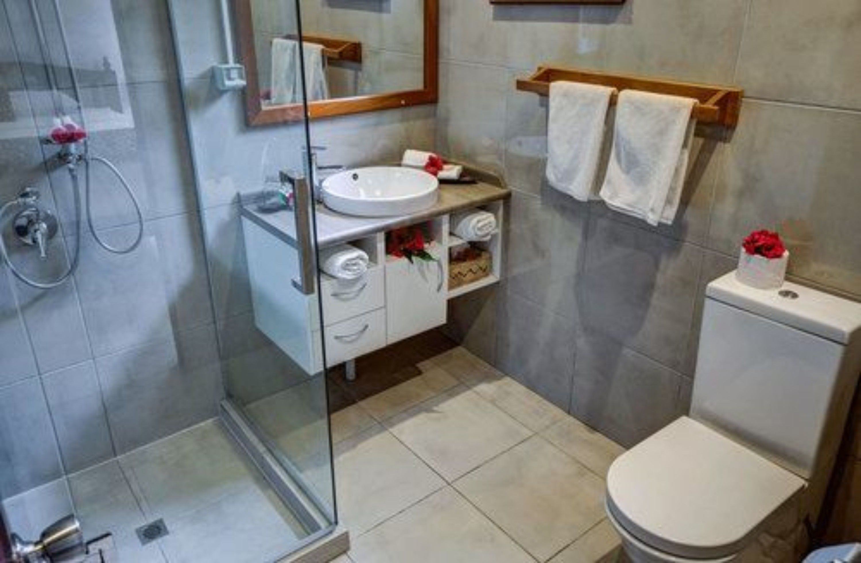 Ein modernes Badezimmer mit Duschkabine aus Glas, einem weißen Waschbecken und einer Toilette.