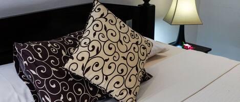 A bed with two patterned pillows and a bedside lamp.