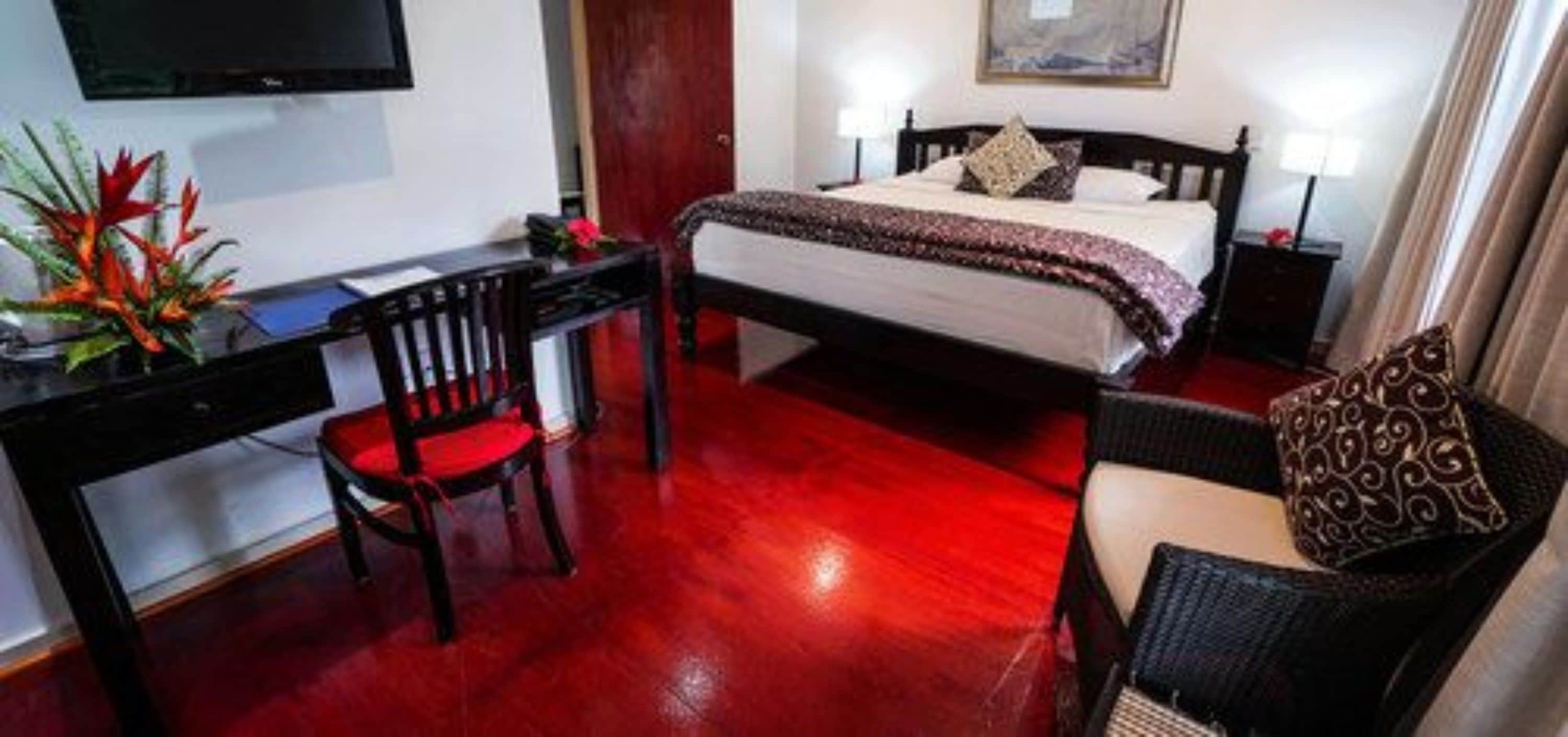 Una habitación de hotel con cama, escritorio, silla y televisor.
