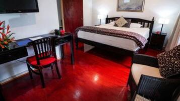 Una habitación de hotel con cama, escritorio, silla y televisor.