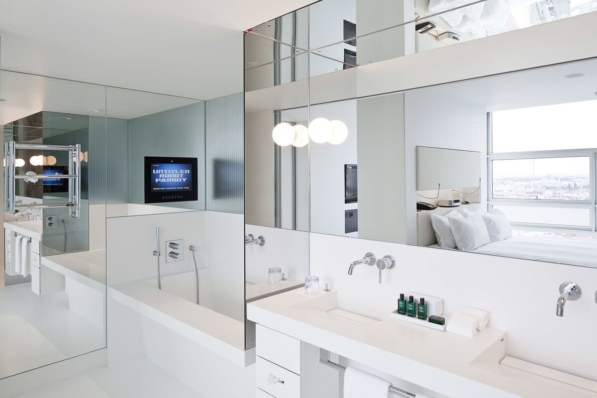 Un baño moderno con un espejo grande, un tocador con lavabo y una zona de ducha.