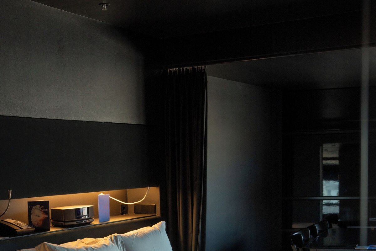 Habitación de hotel moderna con una cama grande, mesita de noche y un espejo.