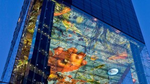 A modern building with a large glass facade reflecting a colorful mural of aquatic life. - SO/ Vienna (Vienna)