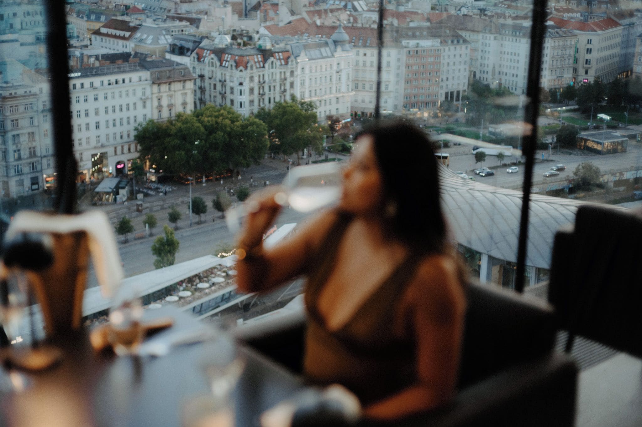 Uma pessoa sentada à mesa com vista para a cidade através de uma janela.