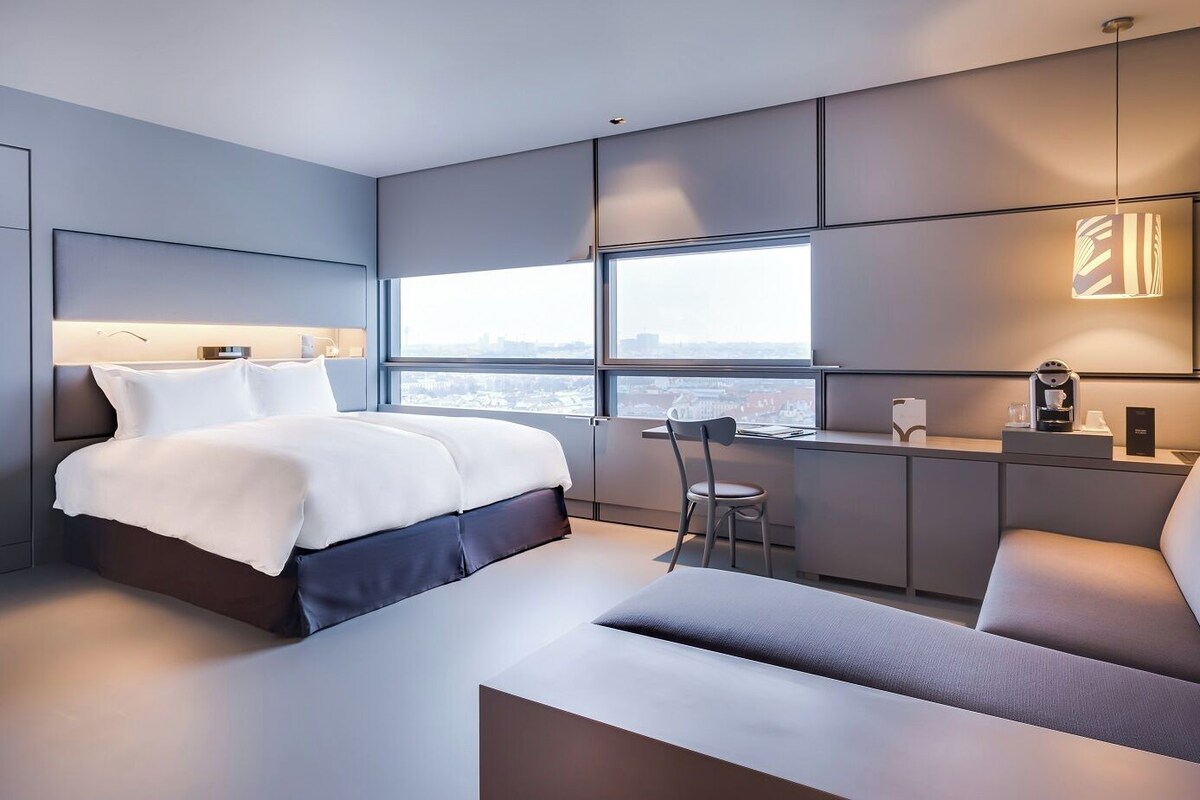 Una habitación de hotel moderna con una cama grande, un escritorio y una silla.