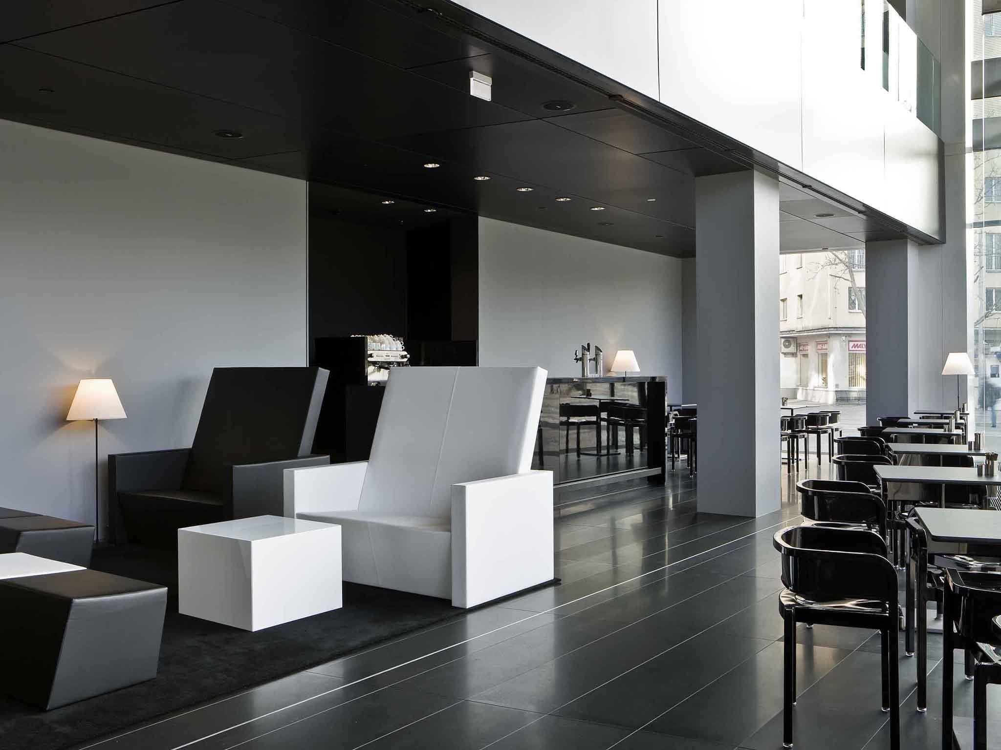 Een moderne lounge met zitplaatsen en tafels, een groot raam en uitzicht op de stad.