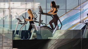 Un gimnasio moderno con dos cintas de correr y un muro de cristal.
